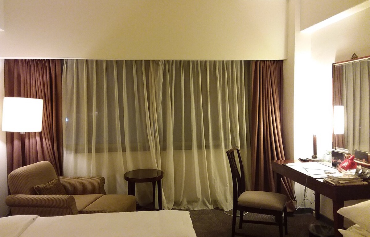 Full-length curtains hanging beside a hotel room window