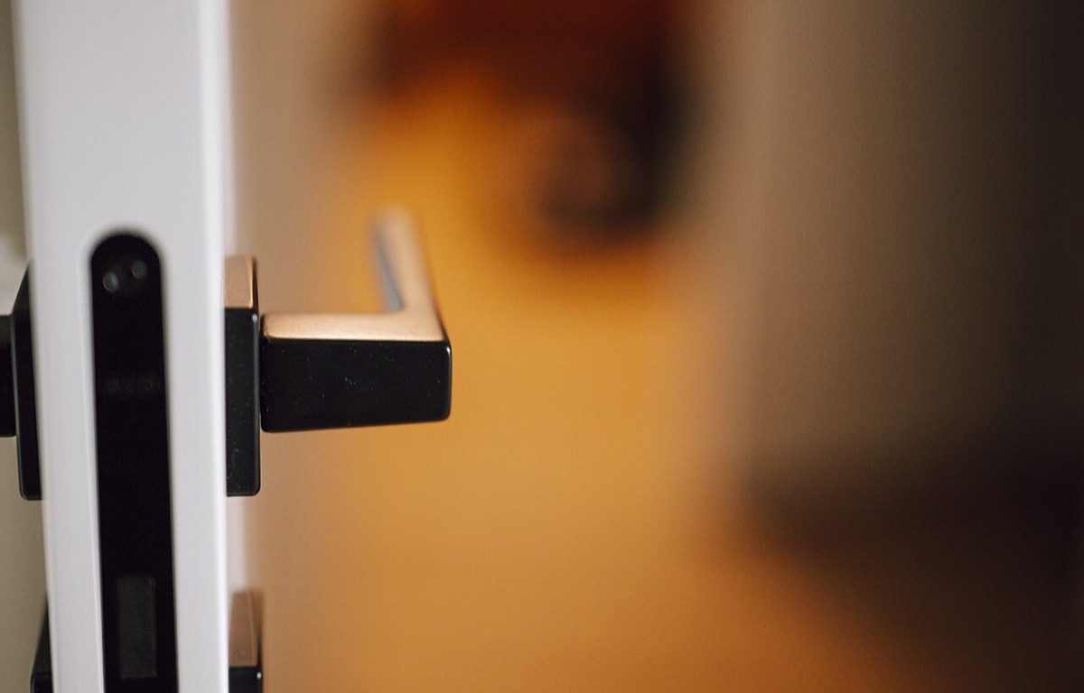 Close view of a metal door handle beside a softly lit hallway
