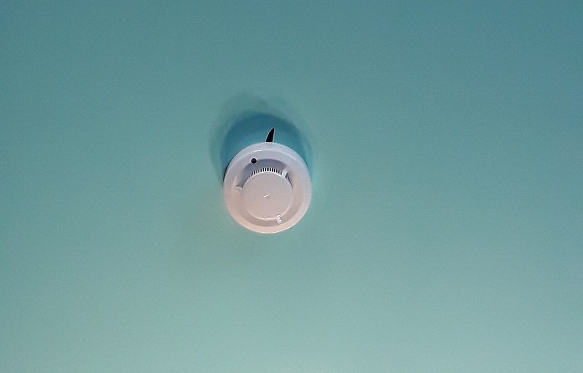 Round smoke detector mounted on a white ceiling