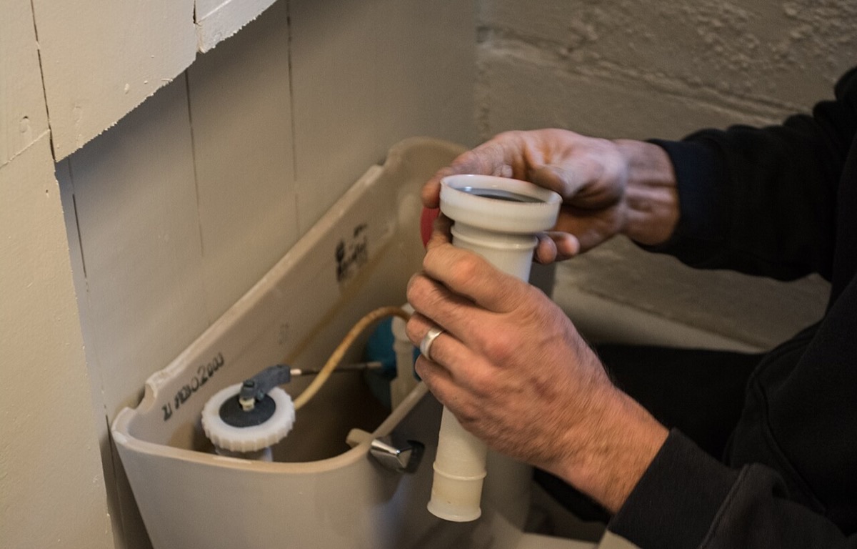 Hands replacing a fill valve inside an open toilet tank